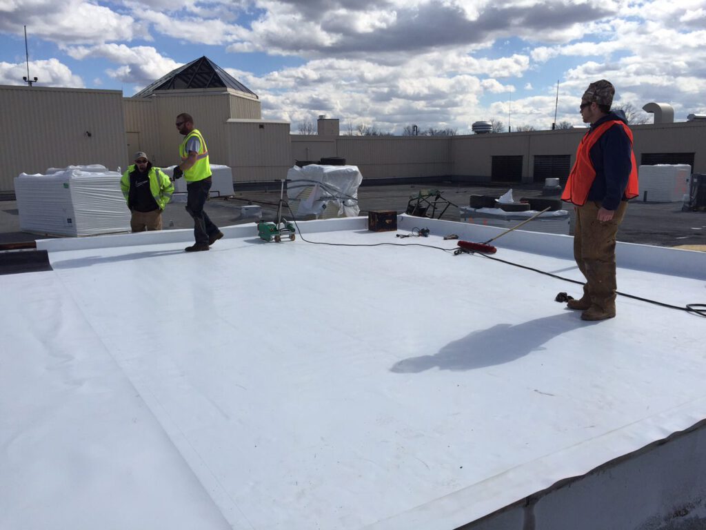 Workers applying TPO roofing